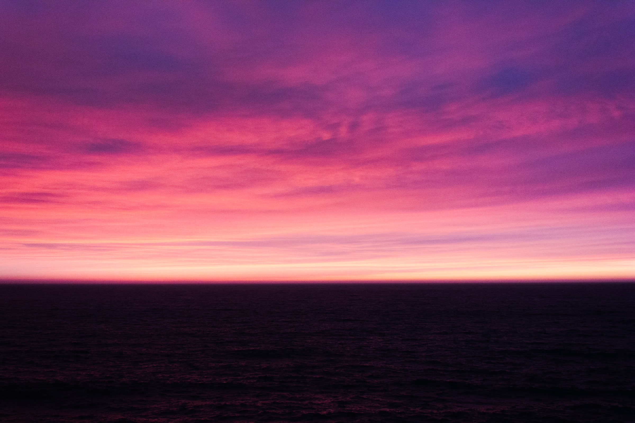Violet and magenta sunset over a dark ocean
