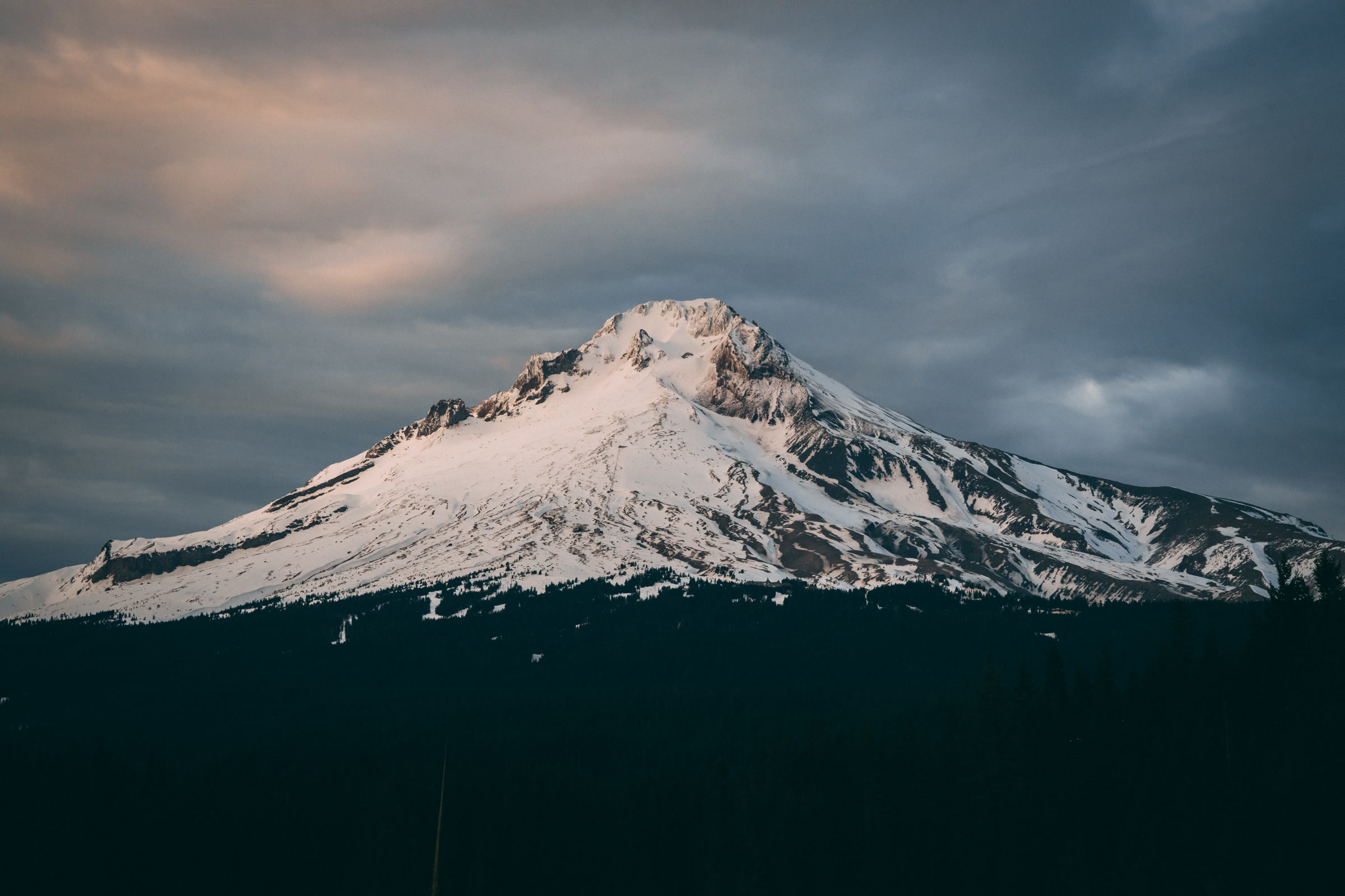 Snow-covered Mount Hood beneath a dramatic sky