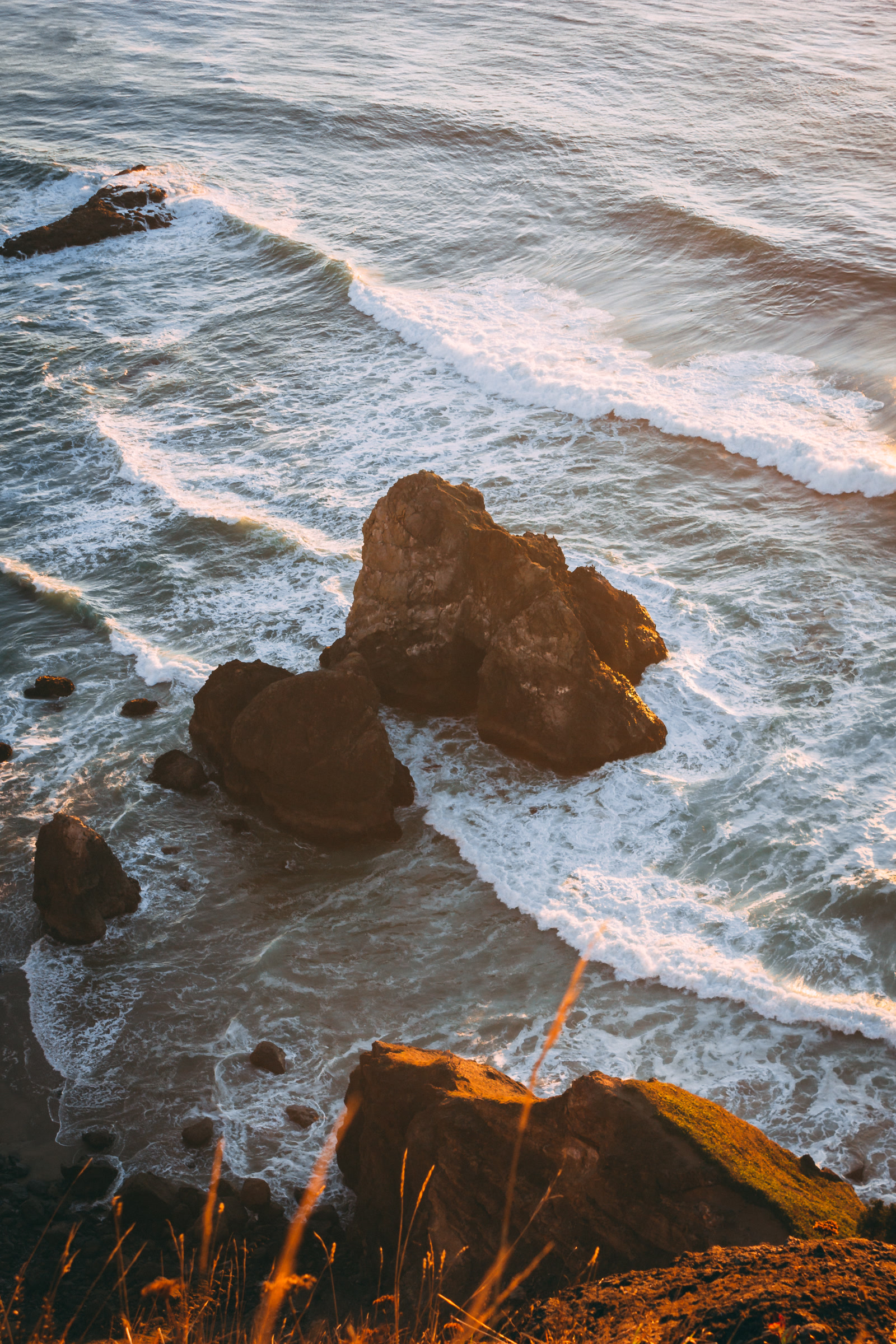 Rock formation in the ocean seen from a cliff at sunset